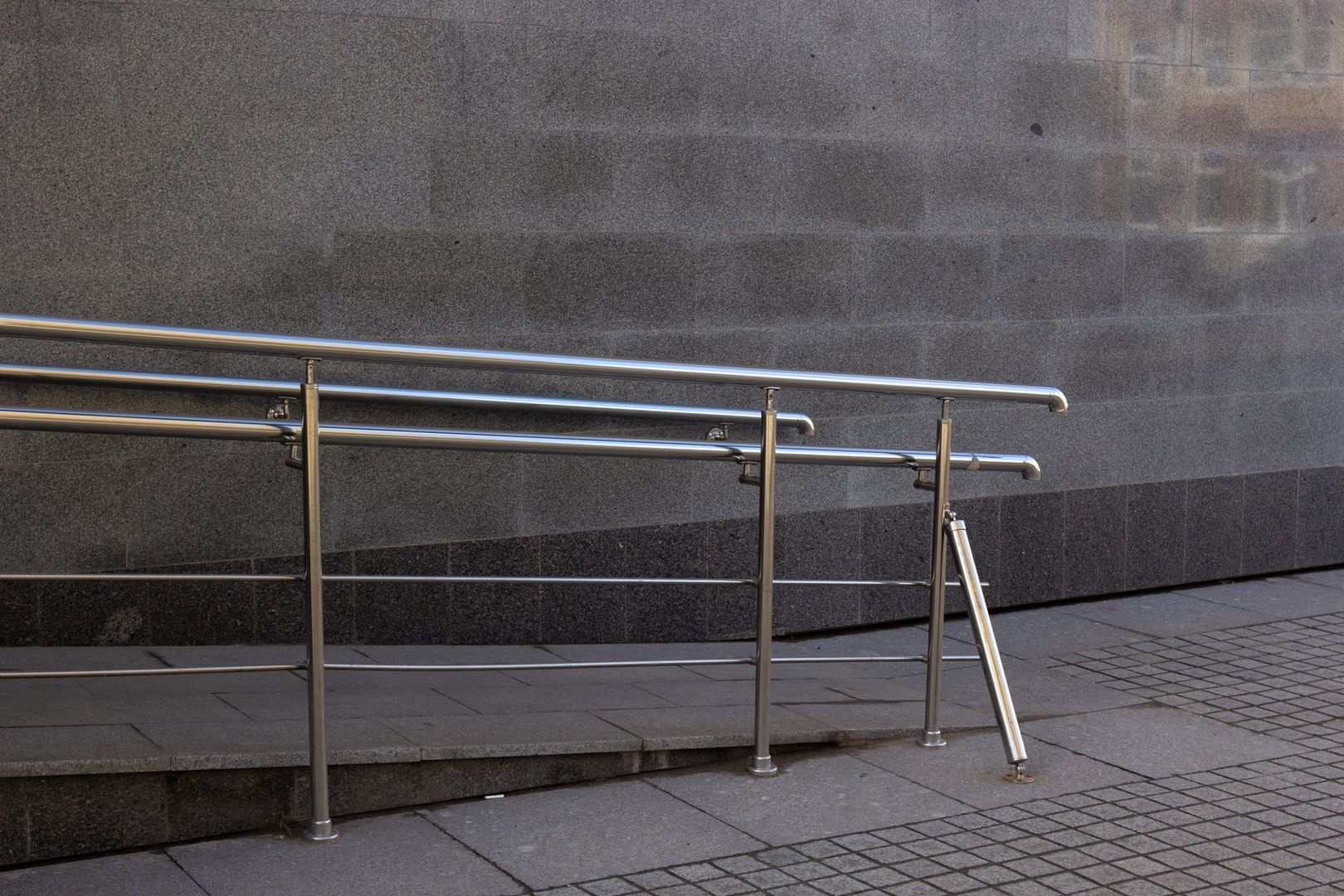 Metallisches Geländer an einer barrierefreien Rampe vor einem Gebäude